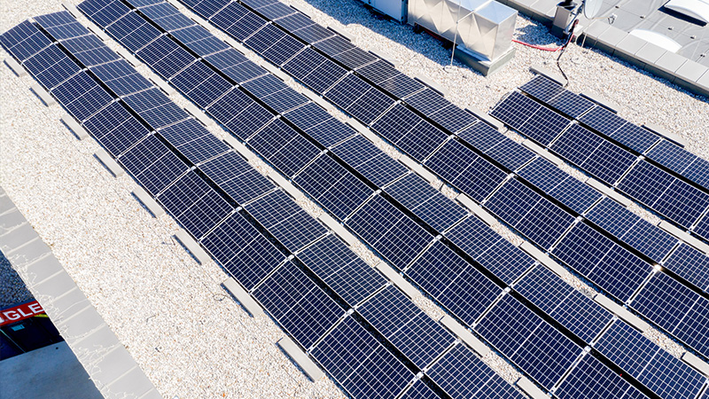 Das Bild zeigt eine Photovoltaikanlage auf einem Flachdach, vermutlich eines Gewerbe- oder Bürogebäudes:
Mehrere Reihen PV-Module, sauber montiert auf Gestellen mit optimalem Neigungswinkel.
Kiesbett als Dachbelag – typisch für Flachdächer zur Beschwerung und Drainage.
Im Hintergrund erkennst du Komponenten der Haustechnik – evtl. Klimageräte oder Lüftungsanlagen.
Das Ganze sieht sehr ordentlich und professionell installiert aus. Hier wird definitiv Sonne in Strom verwandelt, und das ziemlich effizient.