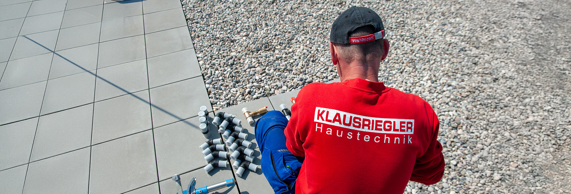 Das Bild zeigt einen Mitarbeiter von KLAUSRIEGLER Haustechnik bei der Arbeit im Außenbereich – eindeutig zu erkennen am Rückenaufdruck und dem Firmenkäppi. Er hantiert mit mehreren Isolierschläuchen, vermutlich für Rohrleitungen oder eine HVAC-Installation (Heizung, Lüftung, Klima).
Das Bild vermittelt:
Handwerkliche Präzision
Professionelles Auftreten
Markenidentität durch Kleidung
Einsatz unter realen Bedingungen (Sonne, Dachfläche)
Perfekt für „Wir packen an“-Statements auf der Website, bei Social Media oder im Recruiting („Werde Teil des Teams“).